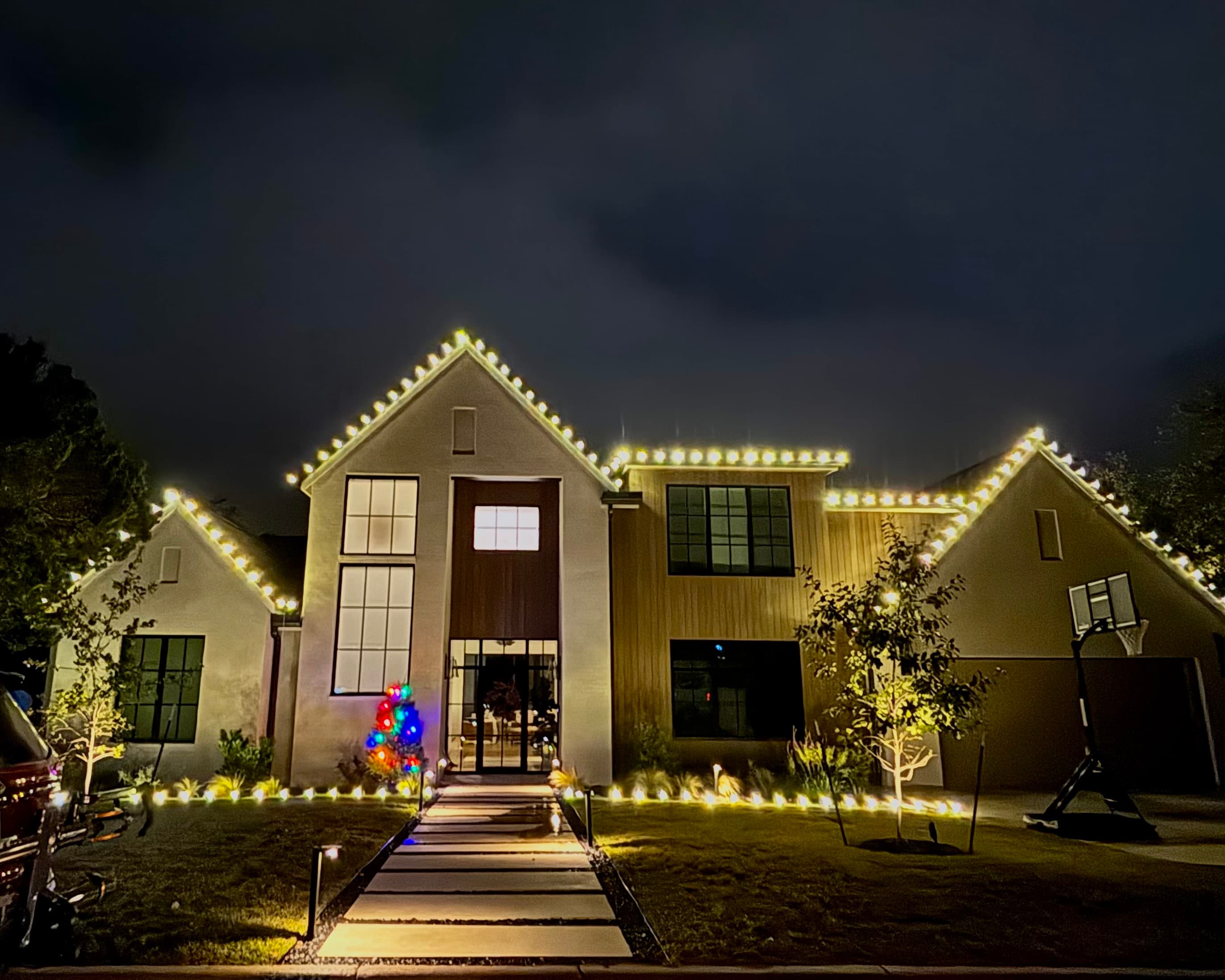 Detail of warm white Christmas lights against an evening sky